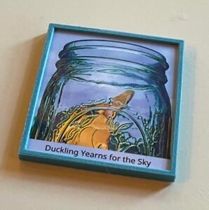 Small framed picture of duckling in a jar