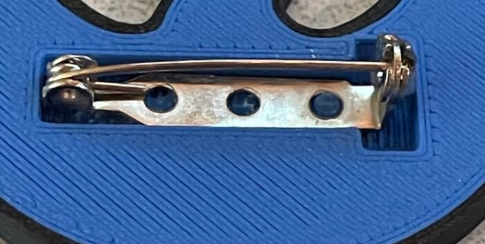 back of badge showing correct installation of pin-back.